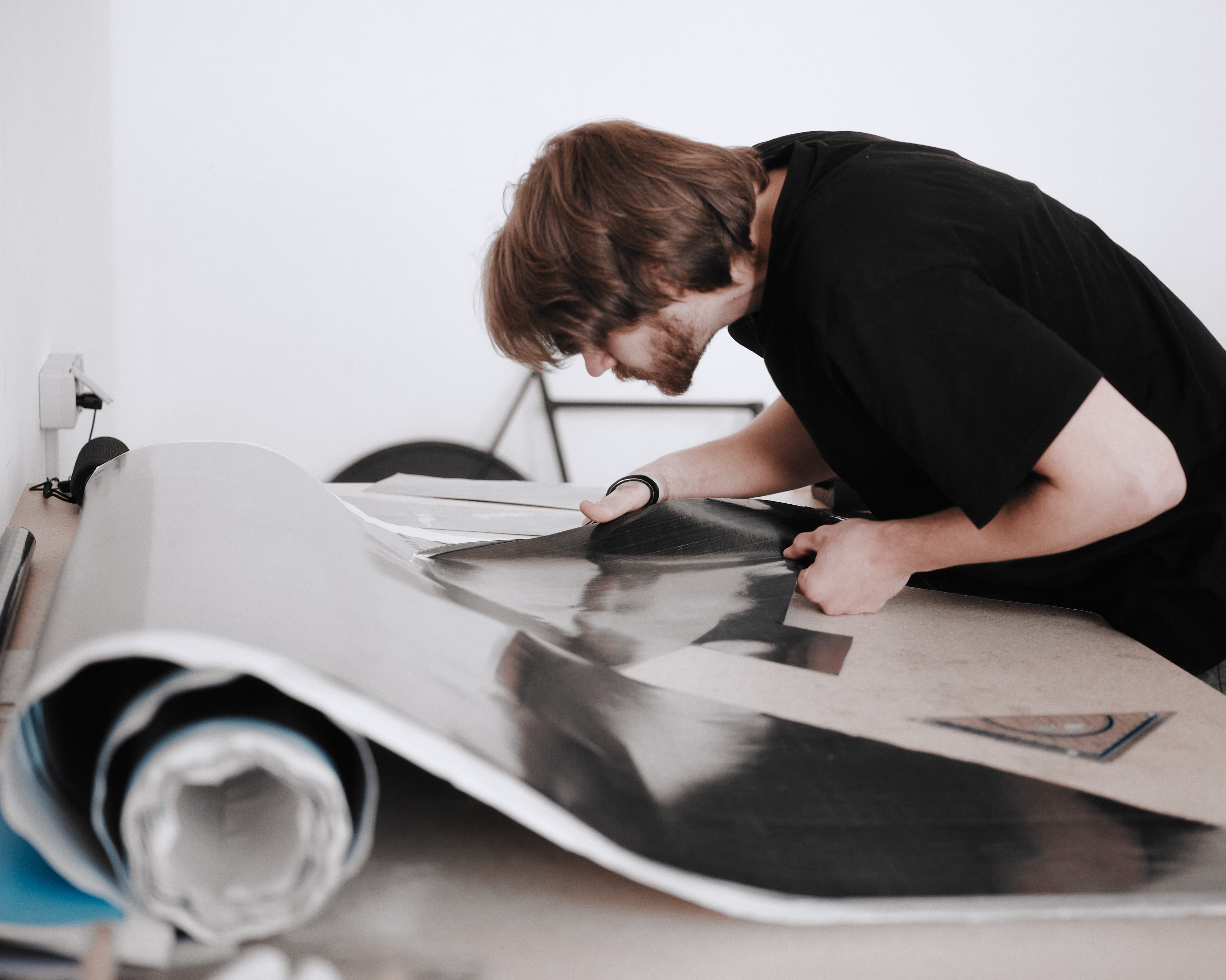 A builder cutting a sheet of carbon fibre on the lay-up table