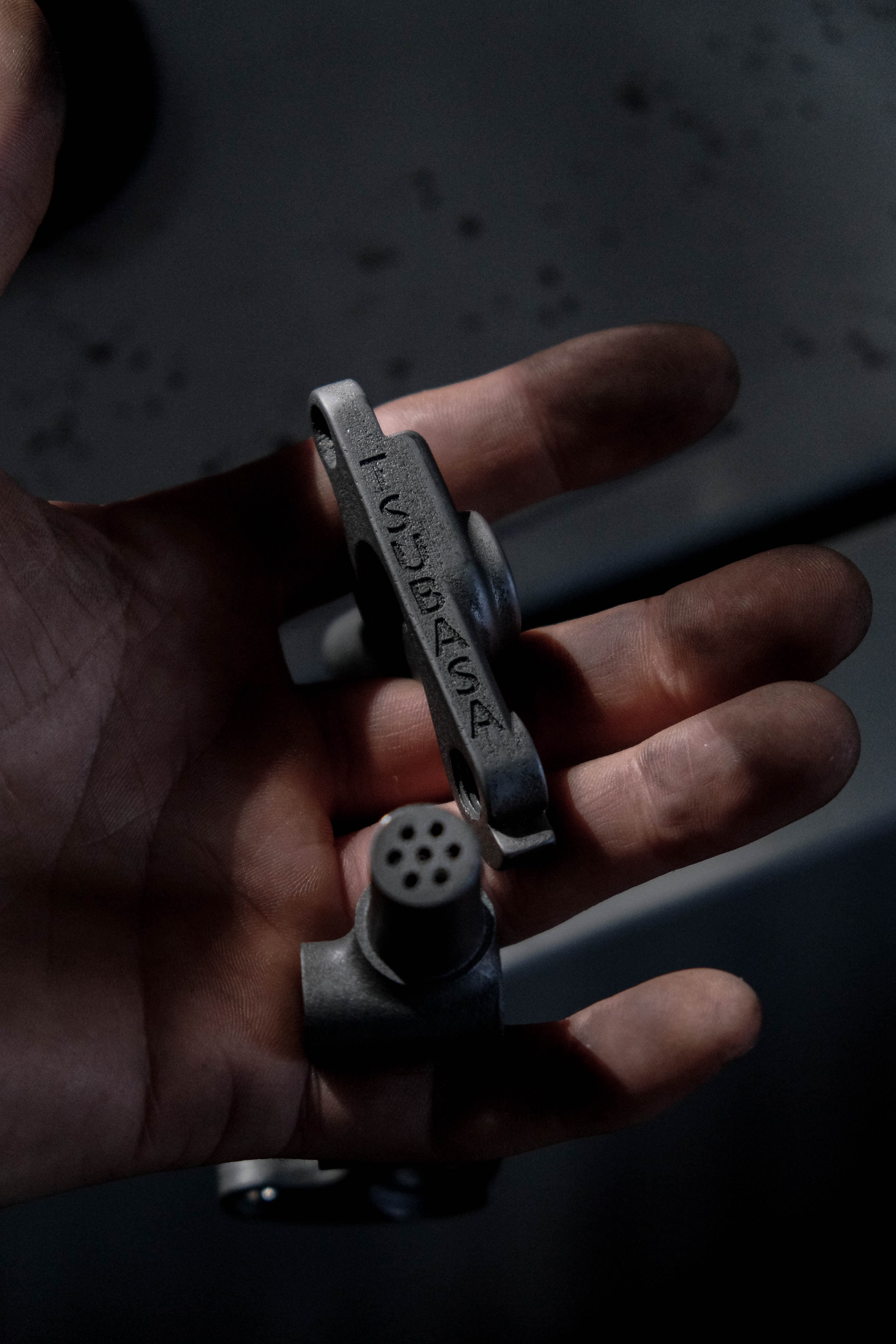 A 3D-printed titanium dropout, the Tsubasa name cast into it, held in an open hand