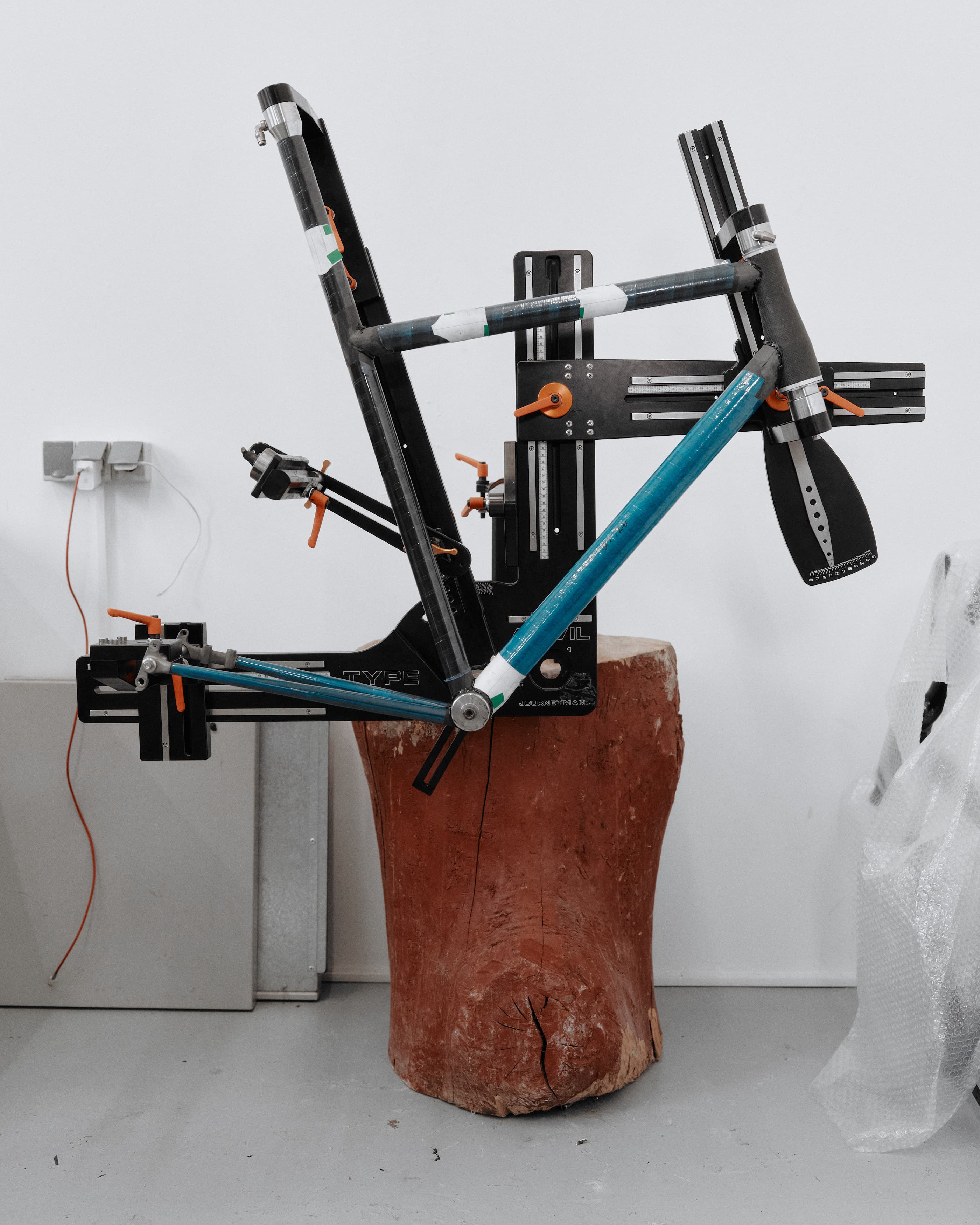 Frame tubes set up in the jig on a tree-stump stand, the geometry fixed before bonding