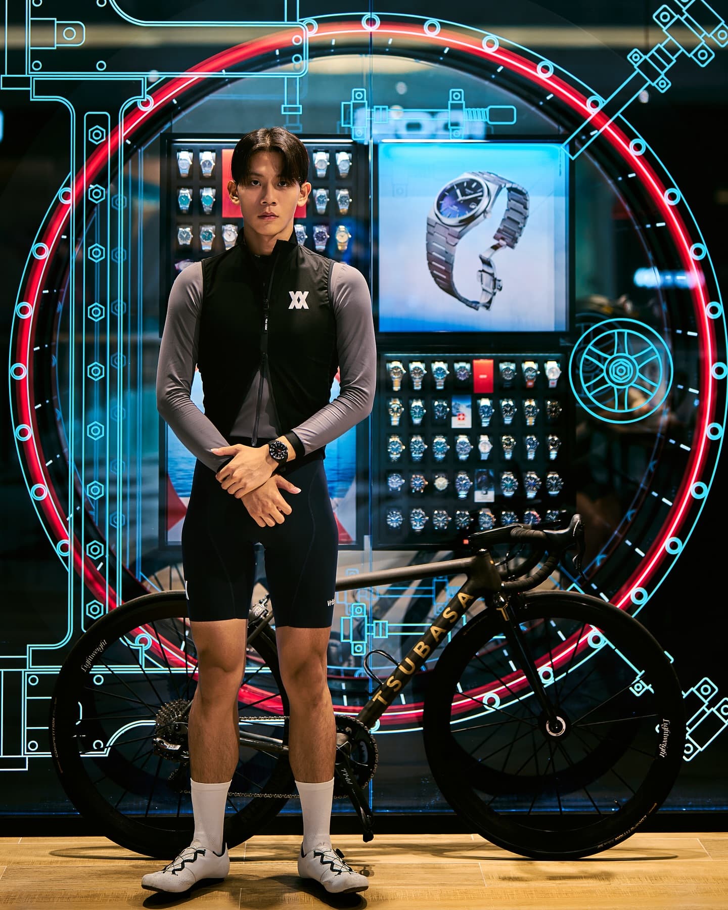 A rider standing with their bike in front of a lit fitting-studio screen