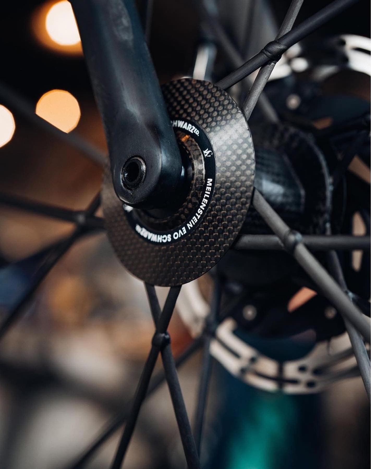 The crank and bottom bracket close in, workshop lights soft behind