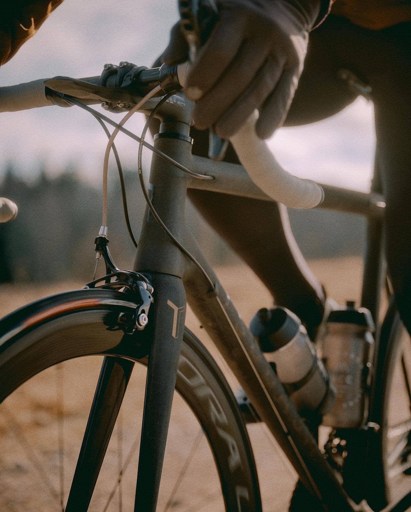 A rider's gloved hands on the bars, close in, dunes beyond